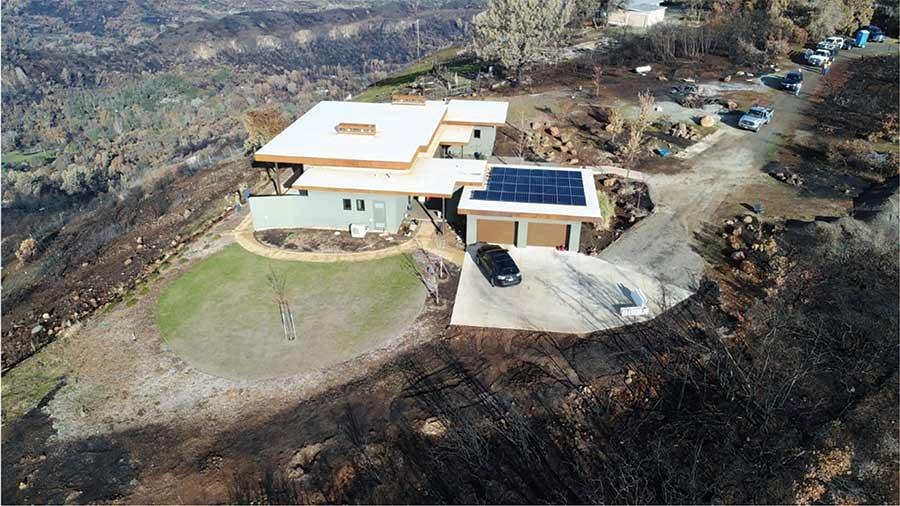 Aerial view of rebuilt home with solar panels in wildfire-damaged area of California